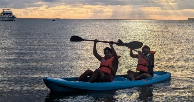 Two kayakers paddling at sunset on scenic coastal waters