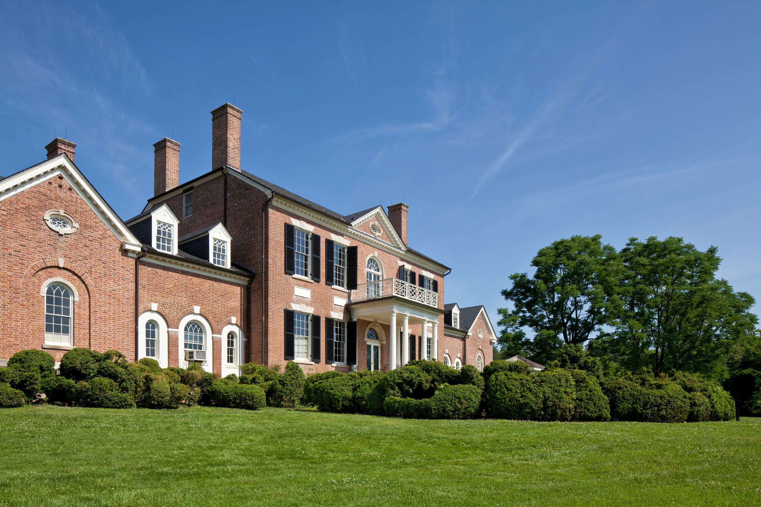 Historic brick estate panorama with manicured grounds and sky