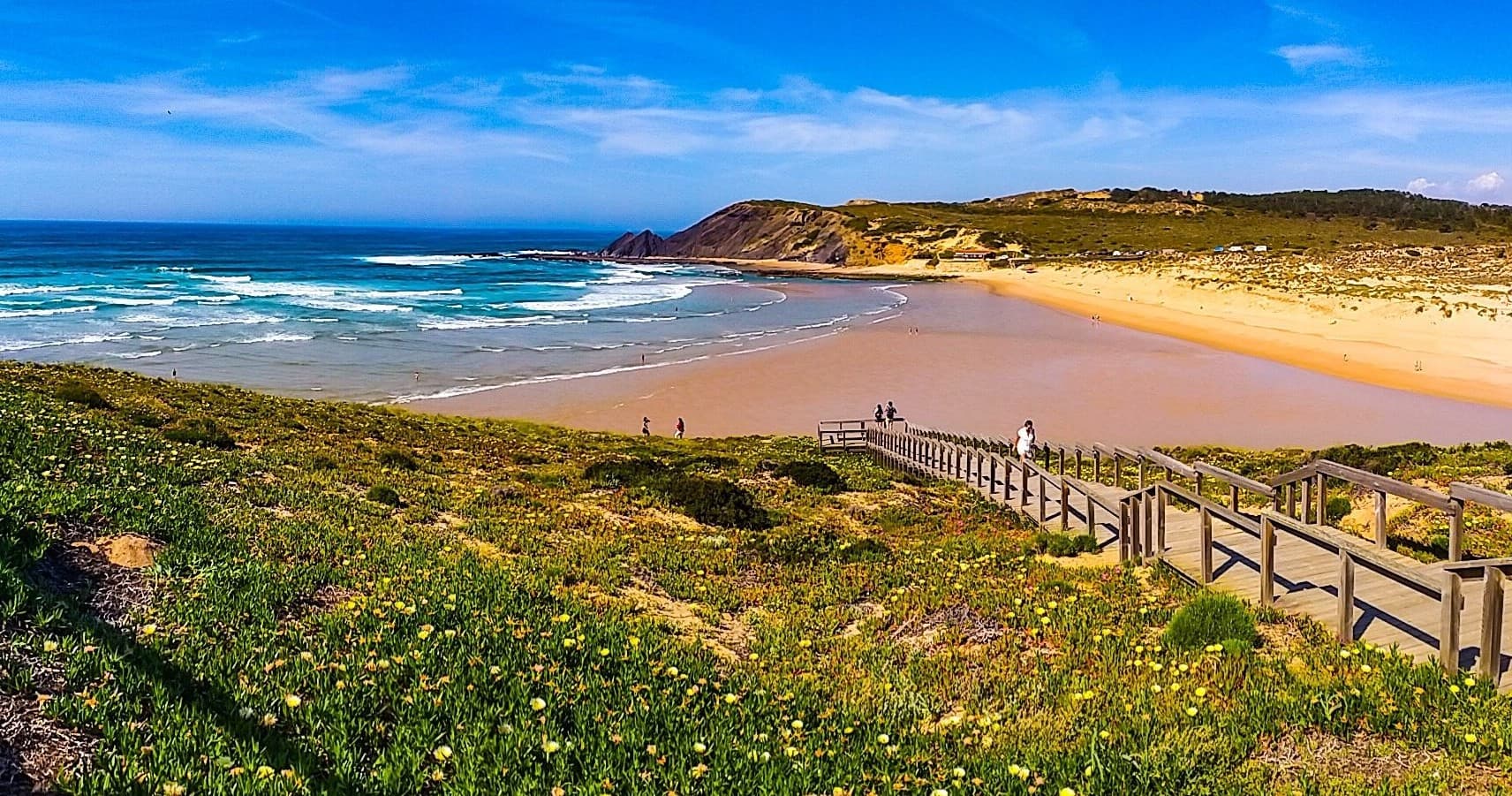 Sandy dune boardwalk leading to expansive golden beach vista