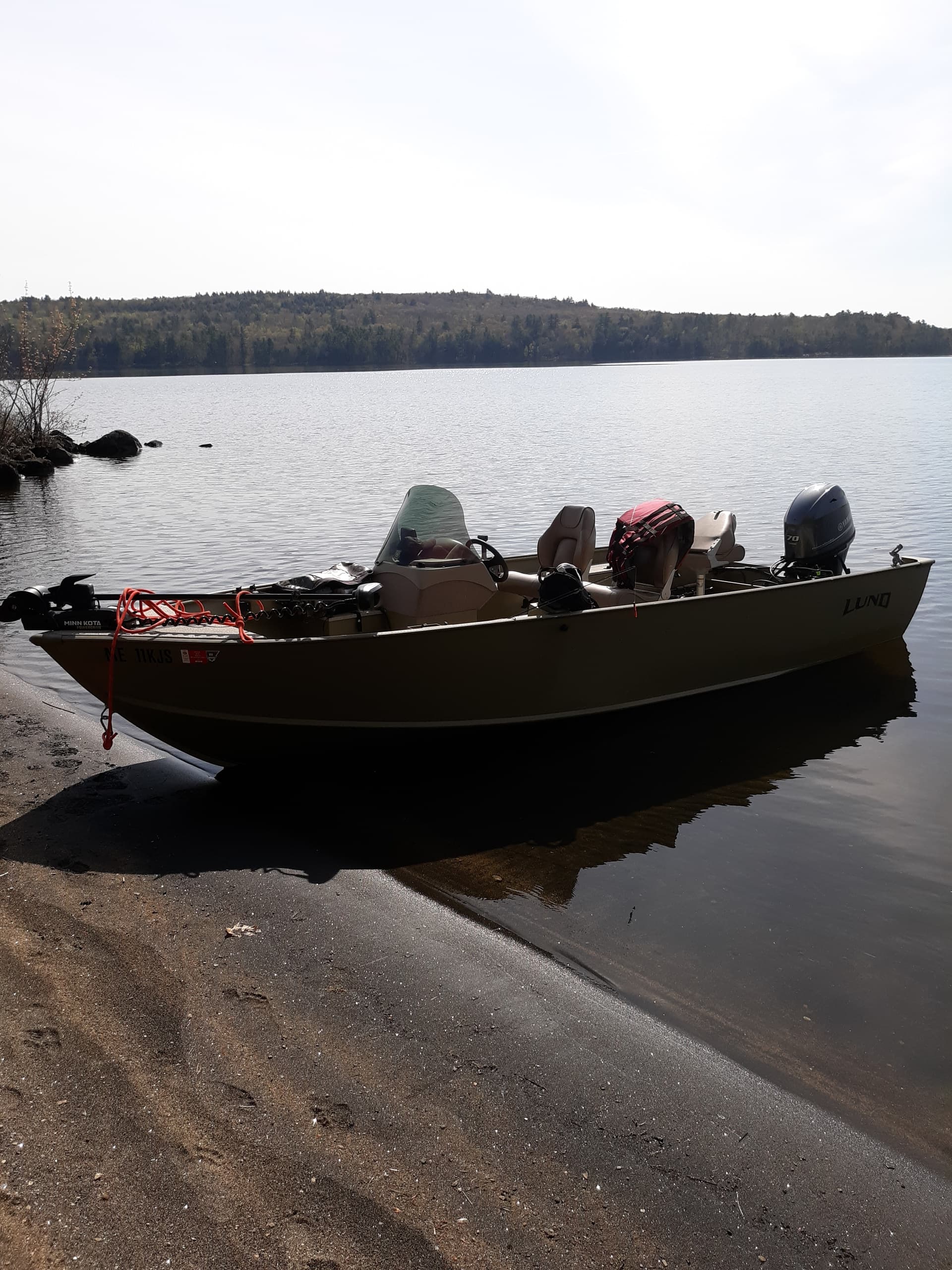 Fishing boat beached on calm forest lake shore at daylight