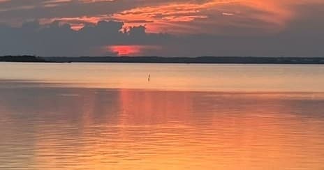 Sunset over calm bay waters at sea, serene boat sunset view