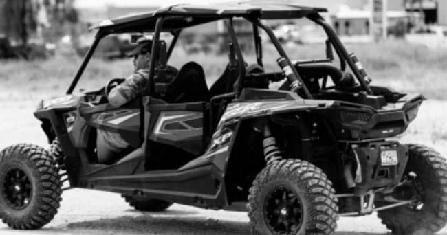 Black-and-white close-up of a rugged off-road UTV in desert