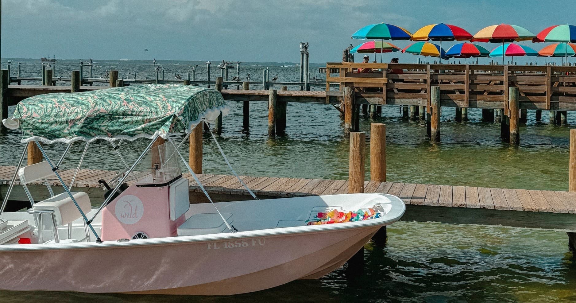 Colorful dock boat near waterfront with beach umbrellas, sunny