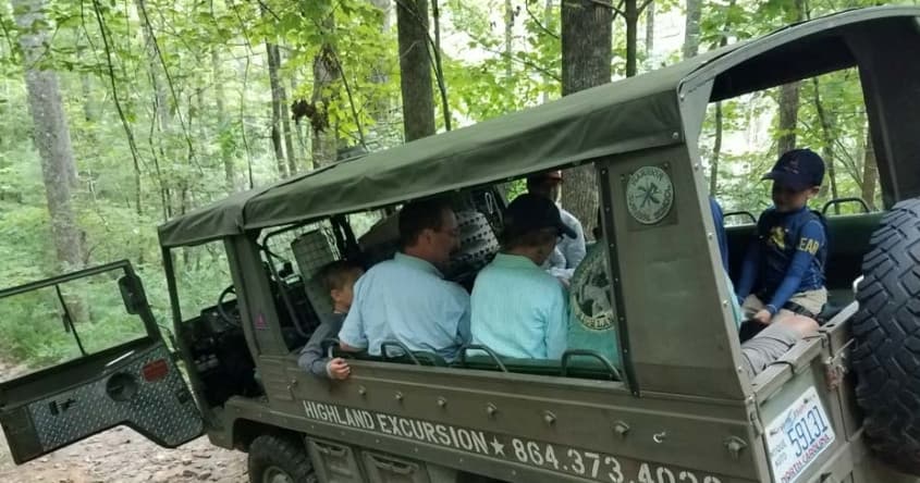 Overland jeep excursion carrying passengers through dense forest trail