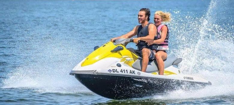 Rider and passenger on yellow jet ski racing across open water