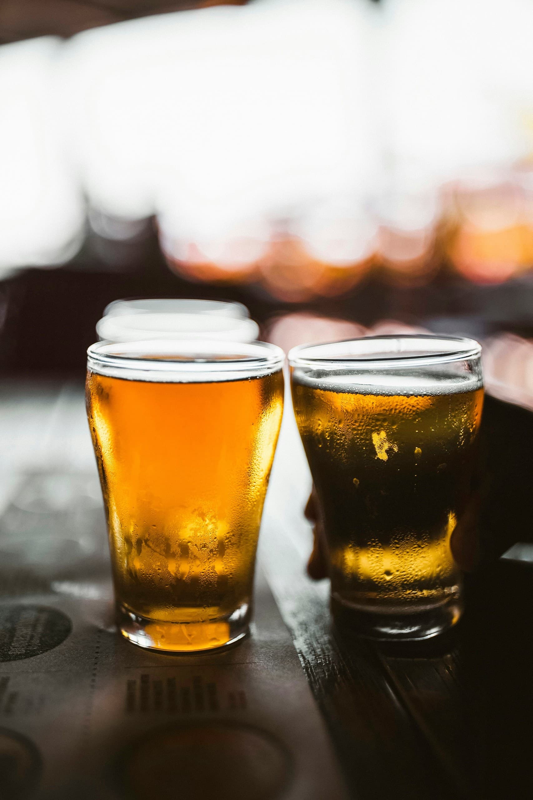 Two amber beers on bar top backlit for rustic craft brewery vibe
