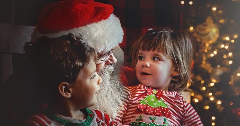 Children sitting with Santa by Christmas tree in cozy portrait