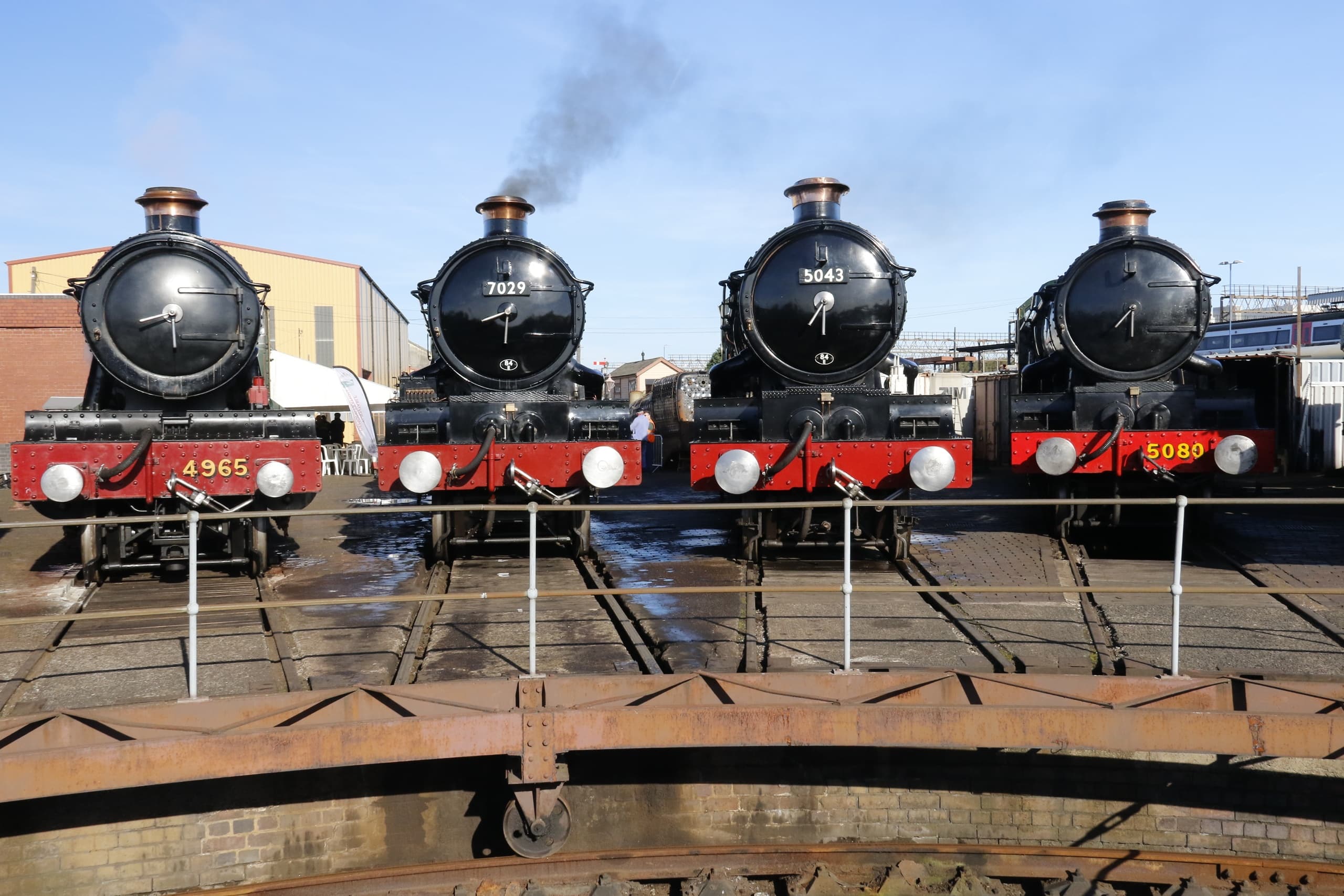 Row of heritage steam locomotives lined up on turntable at depot