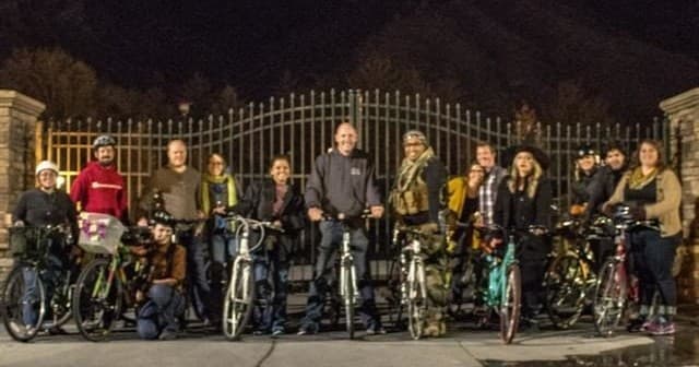 Group of cyclists at night posing with bikes, organized urban bike tour