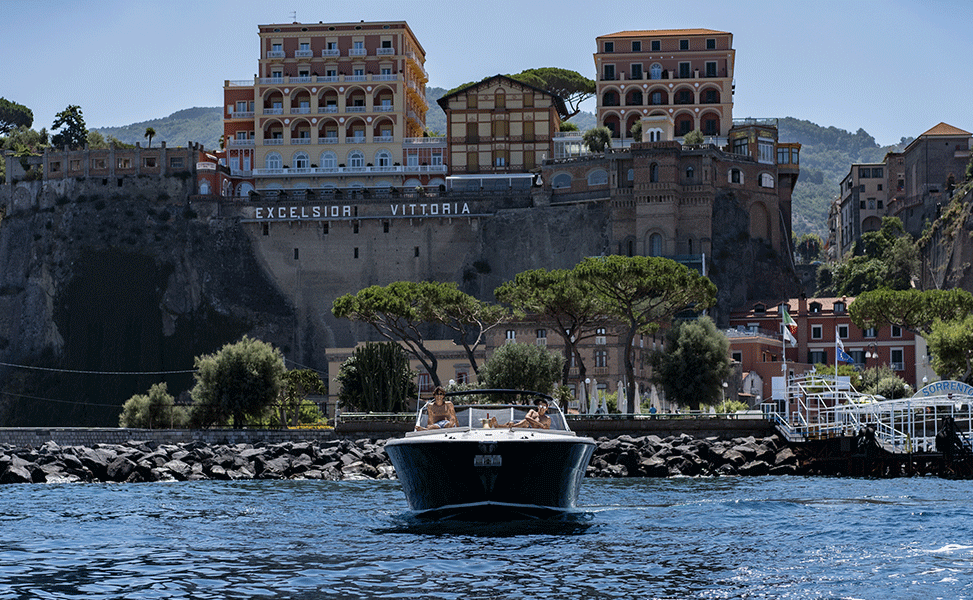 Coastal boat approaching cliffside town and harbor near Sorrento