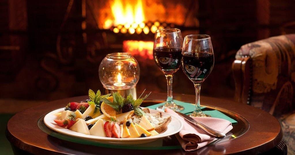 Cozy fireplace dinner setup with wine and cheese in lodge