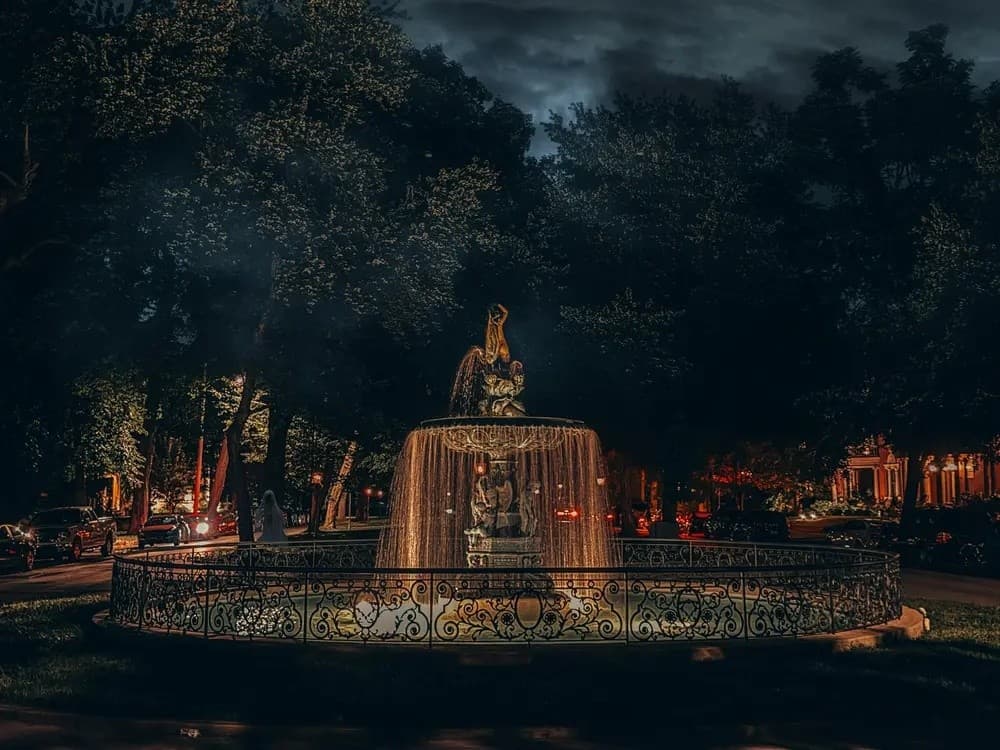 Park fountain at dusk with lit paths for evening walks