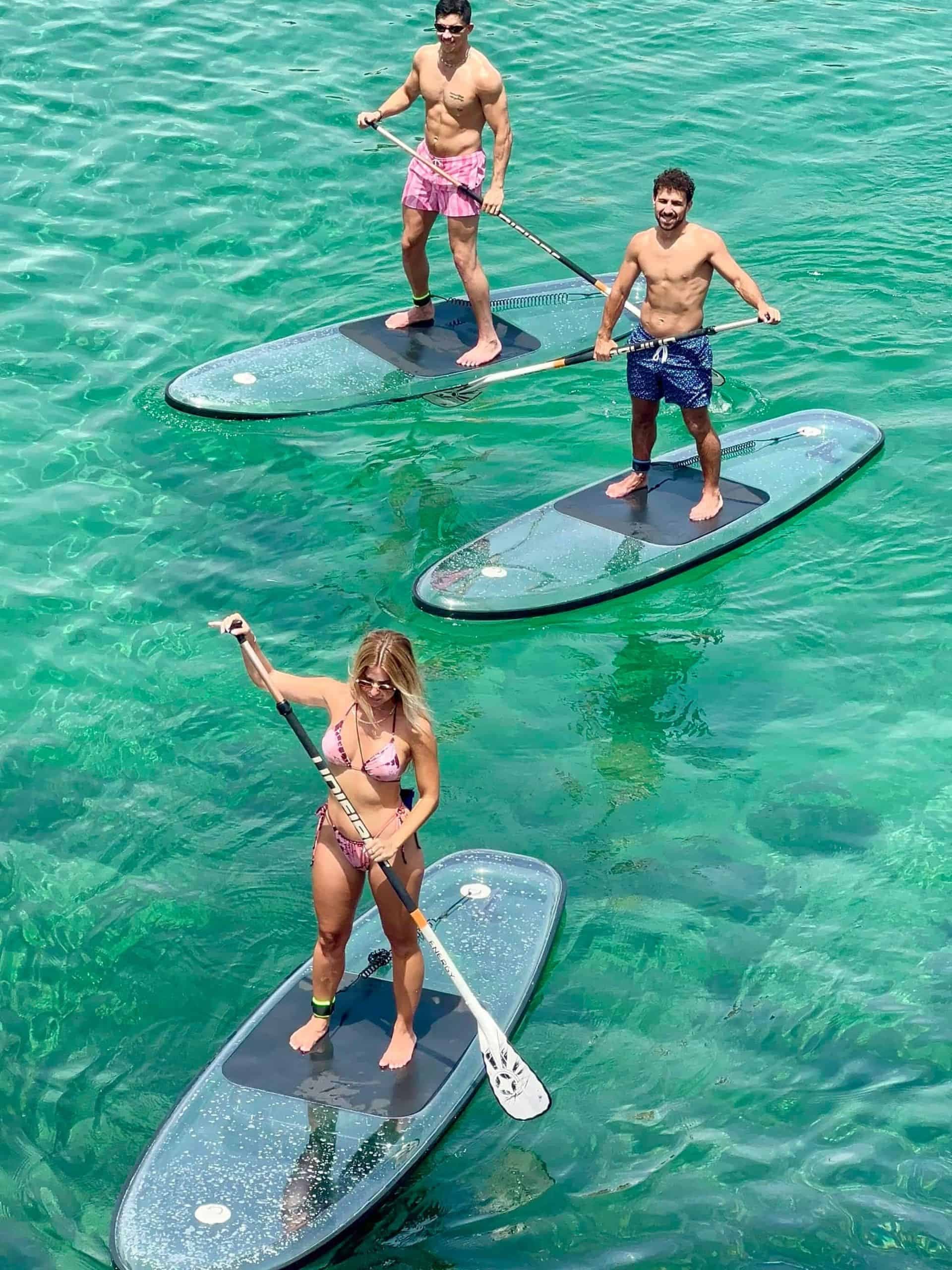 Three people paddleboarding on clear emerald tropical water