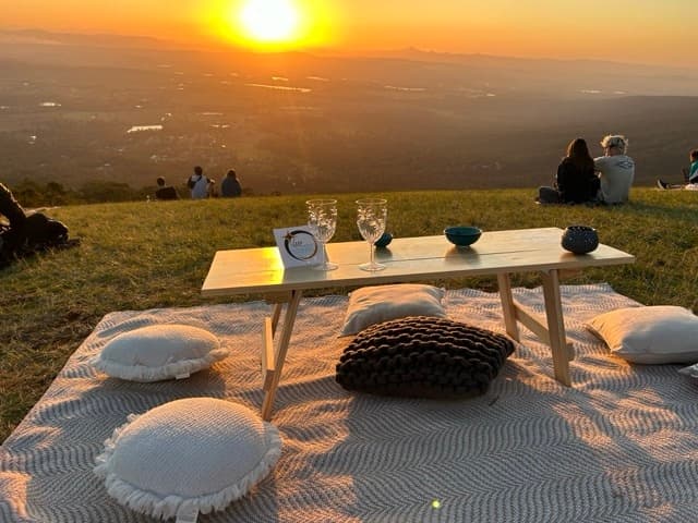 Sunset picnic on hilltop overlooking a scenic valley with cushions