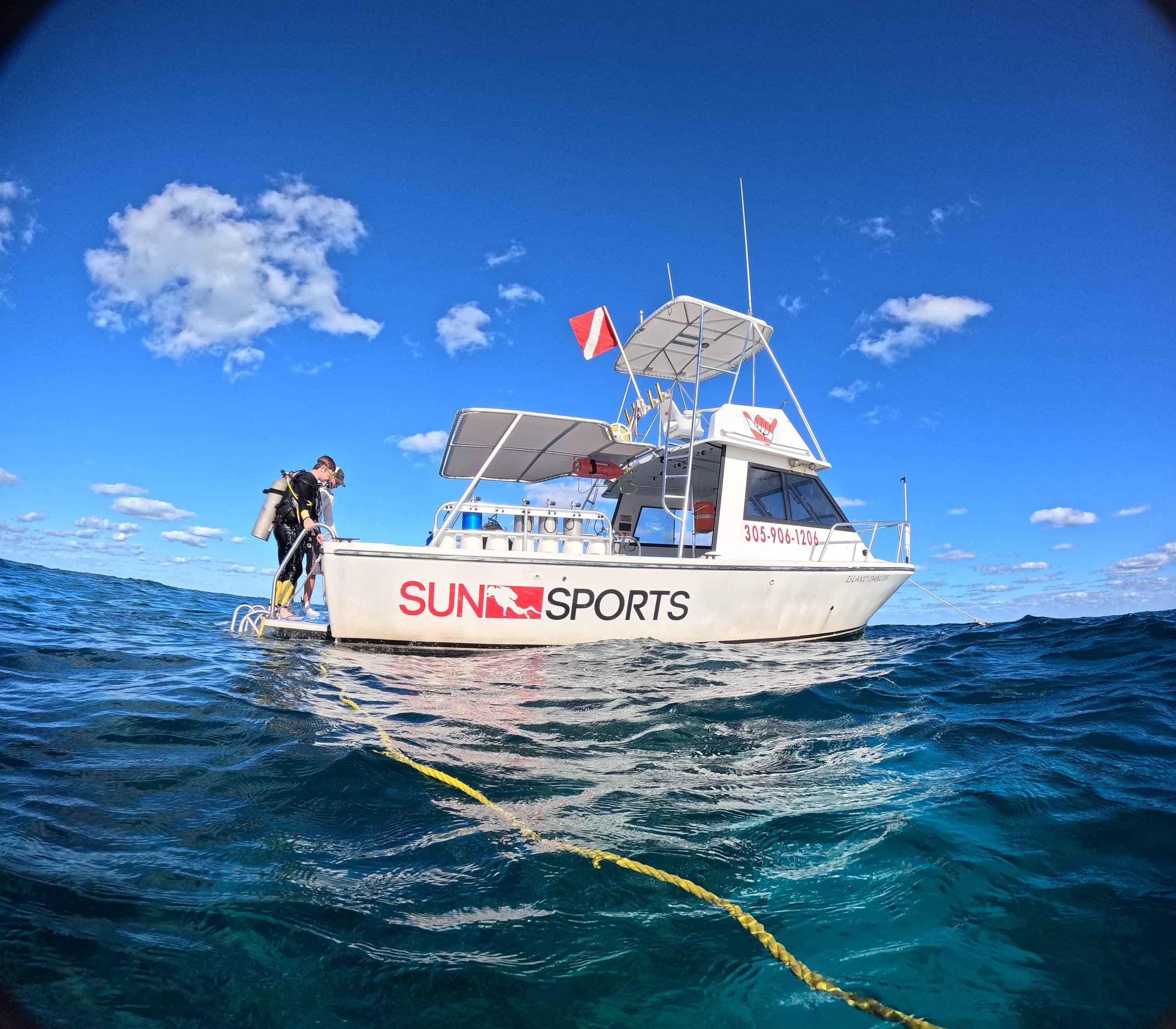 Sport dive vessel with crew near buoy on open ocean, prepping dive
