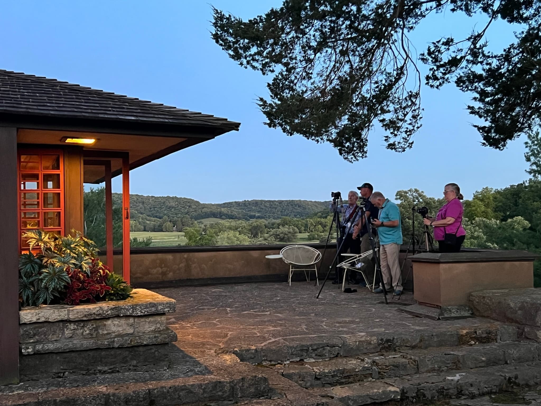 Terrace gathering at sunset overlooking wooded valley landscape