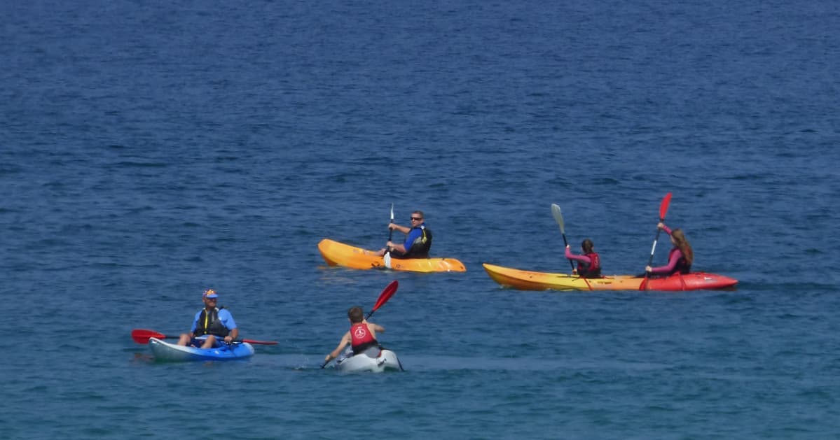 Sea kayakers paddling together on deep blue ocean waters