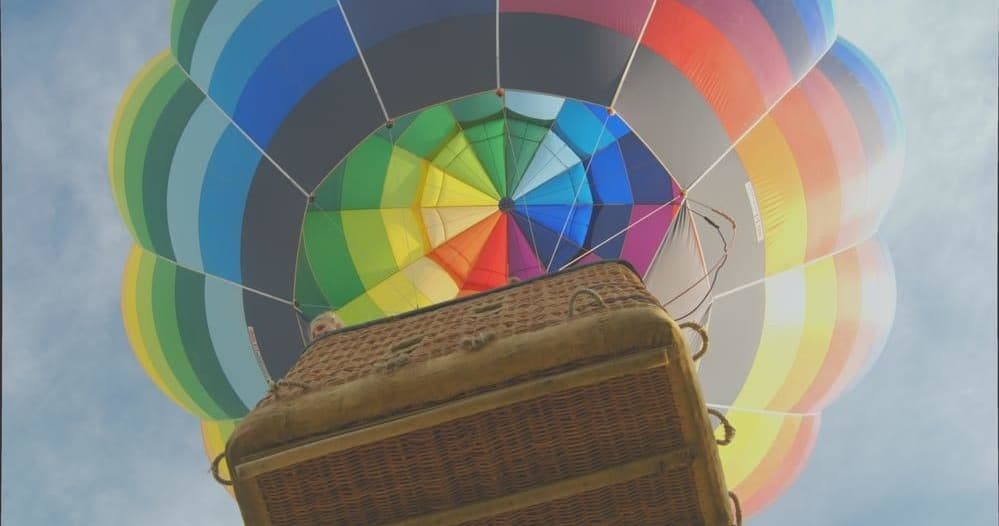 Passengers in hot air balloon basket with vibrant canopy