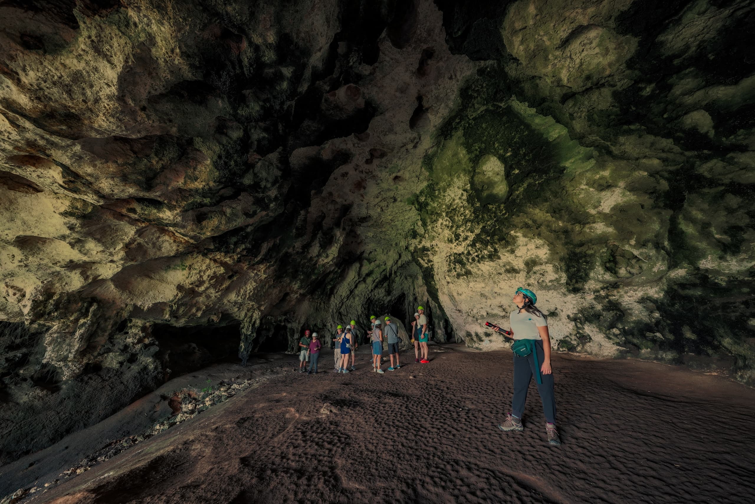 Large coastal cave interior with guided tour group, spelunking
