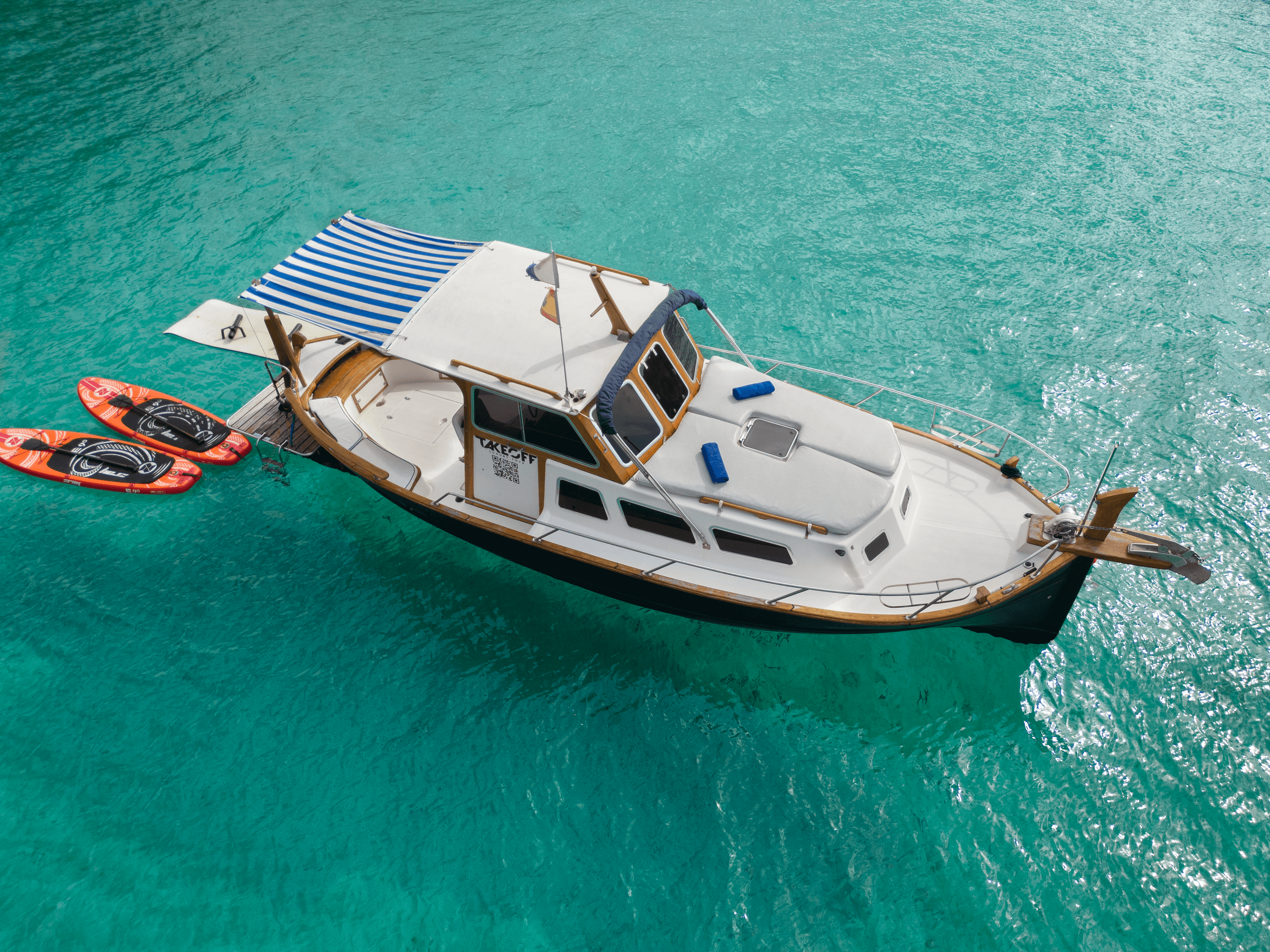 Small motorboat moored in crystal turquoise waters off rocky coast