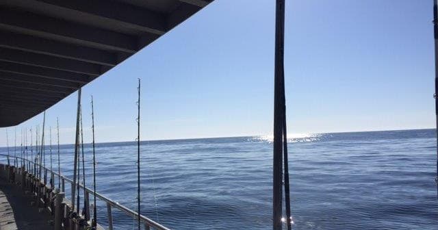 Open-sea view from boat rail with calm ocean and sky