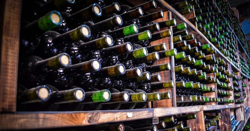 Rows of wine bottles in wooden cellar racks at a winery