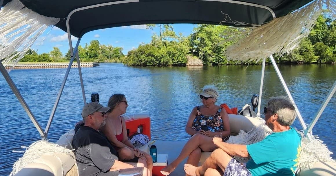 Group relaxing on covered yacht cruising a scenic river