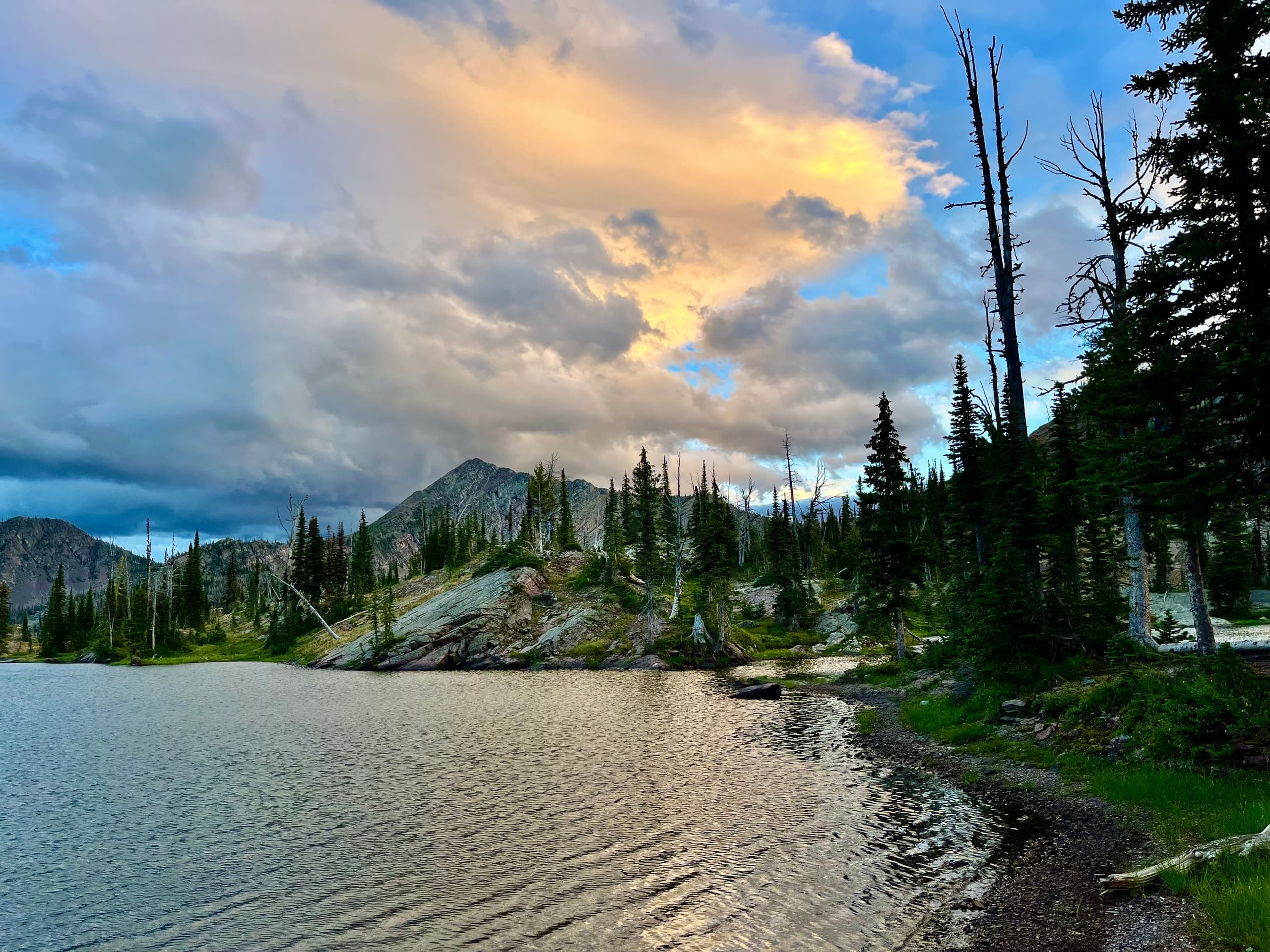 Alpine lake at sunset with forested shoreline and mountain views