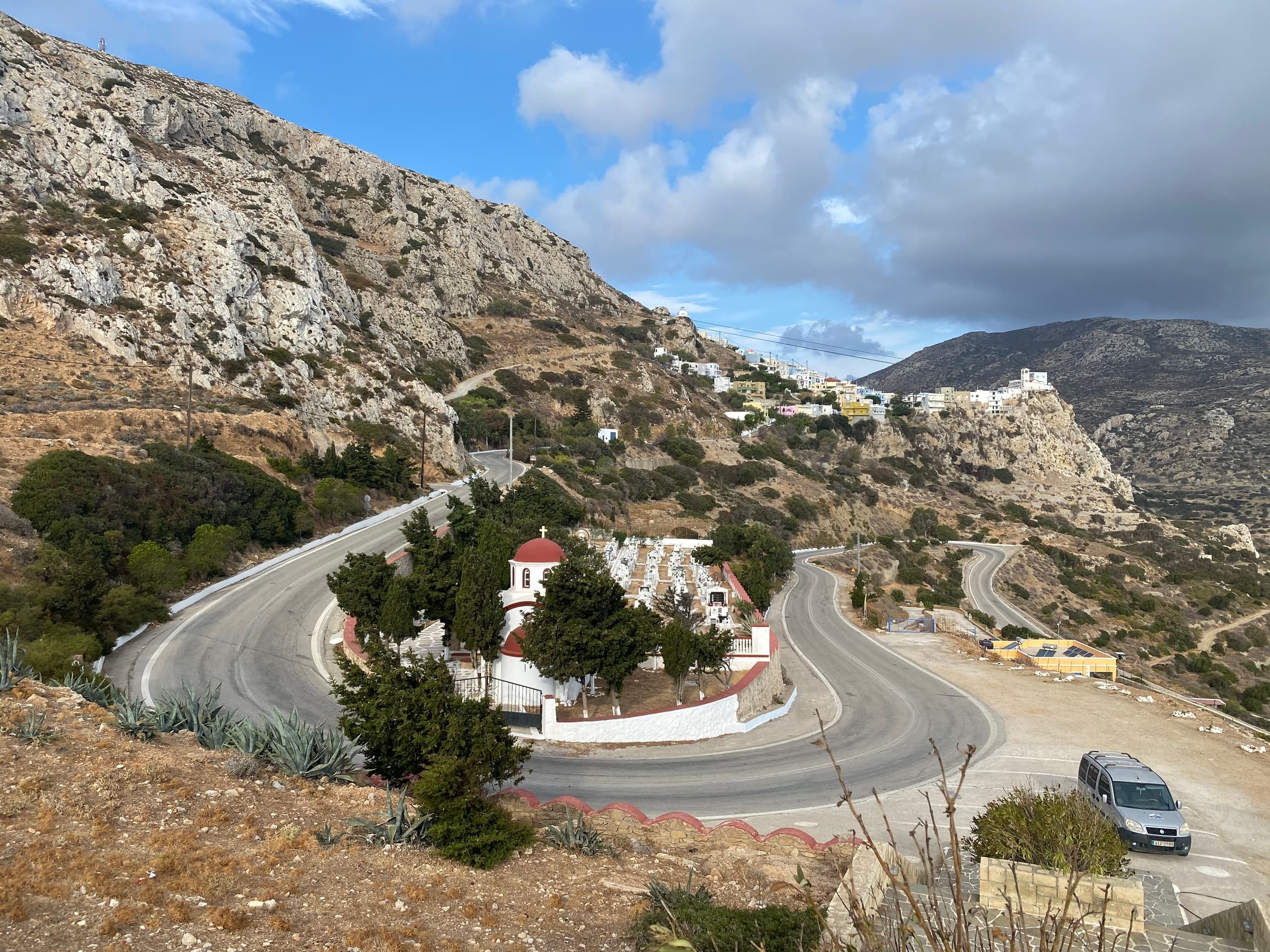 Hikers' viewpoint at winding mountain road by chapel on coast