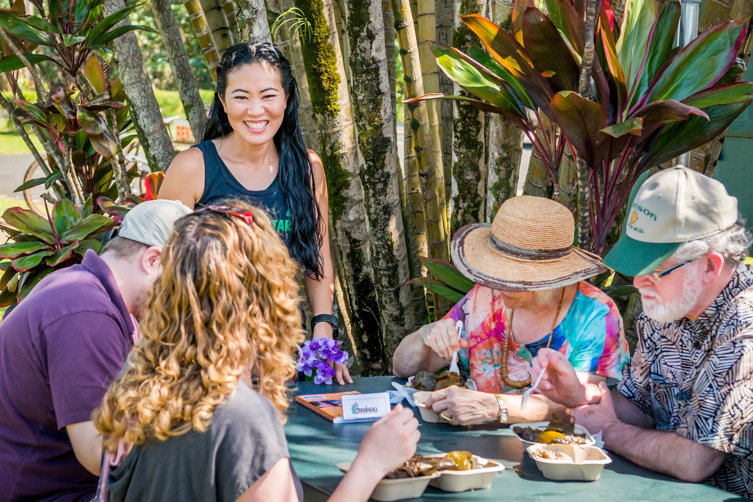 Small-group food tasting under tropical palms at outdoor table