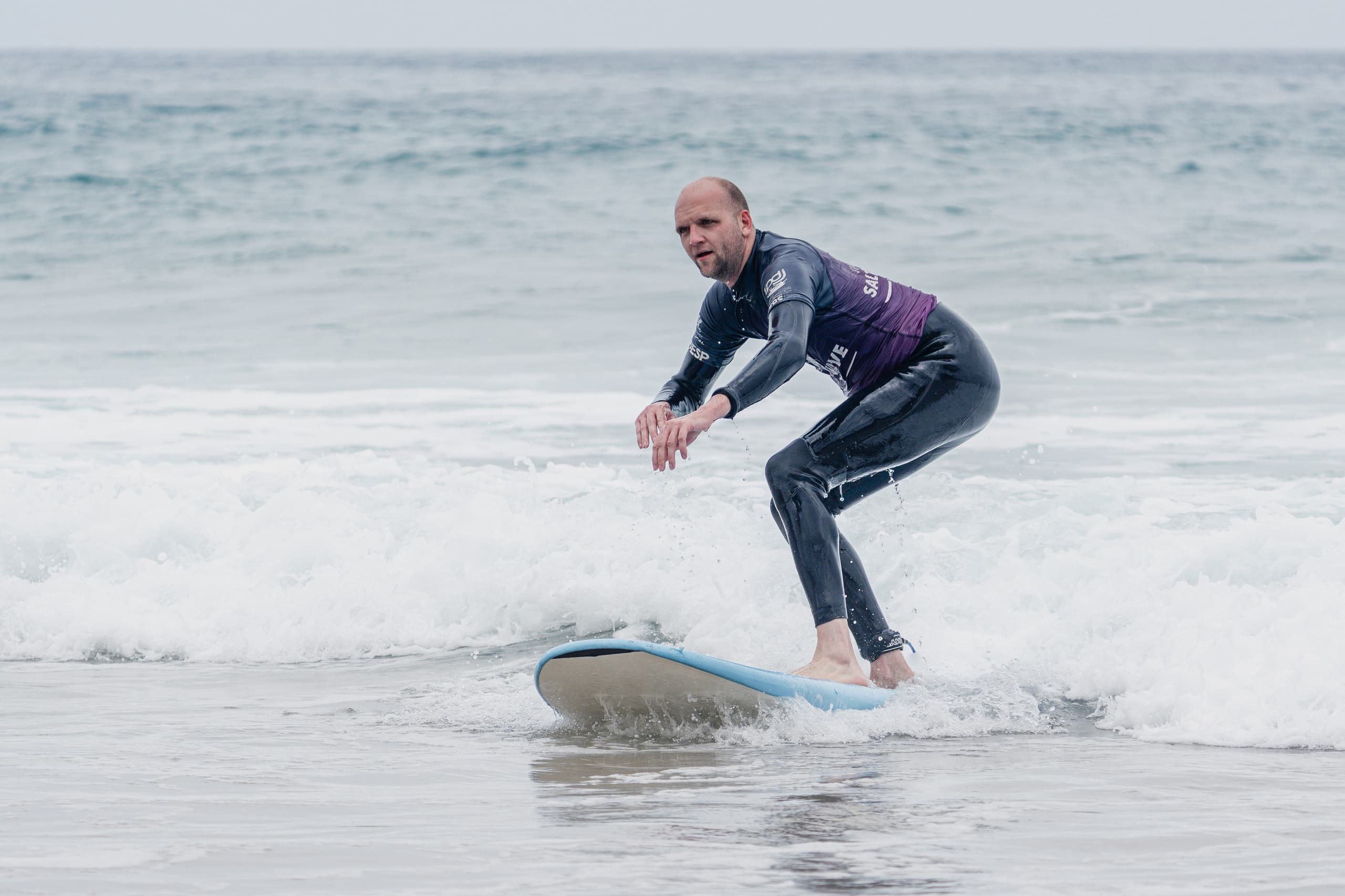 Male surfer balancing on board while riding a small breaking wave