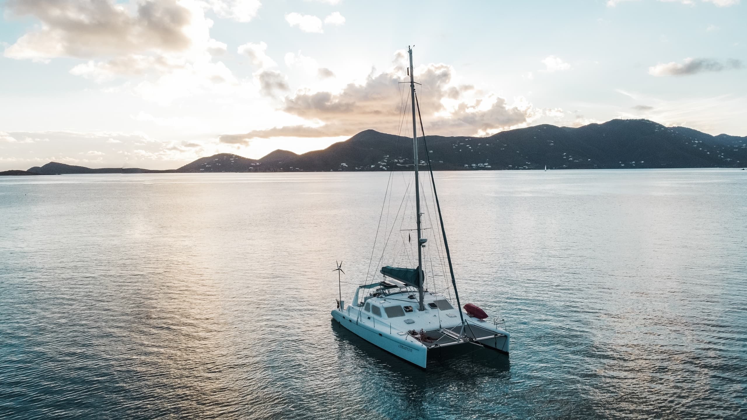 Catamaran sailing at sunset near tropical island coastline
