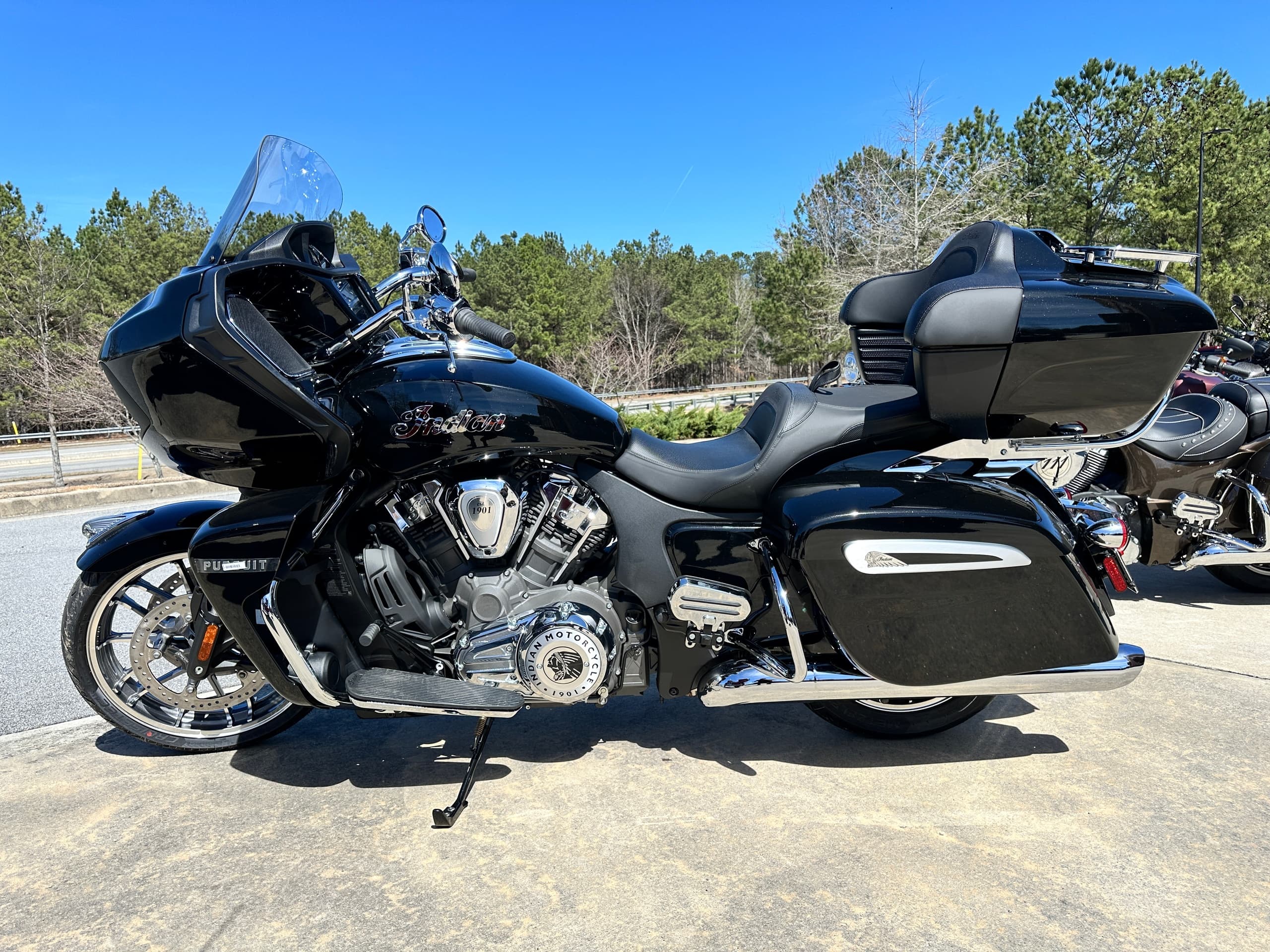Black Indian bagger motorcycle parked in sunny dealership lot