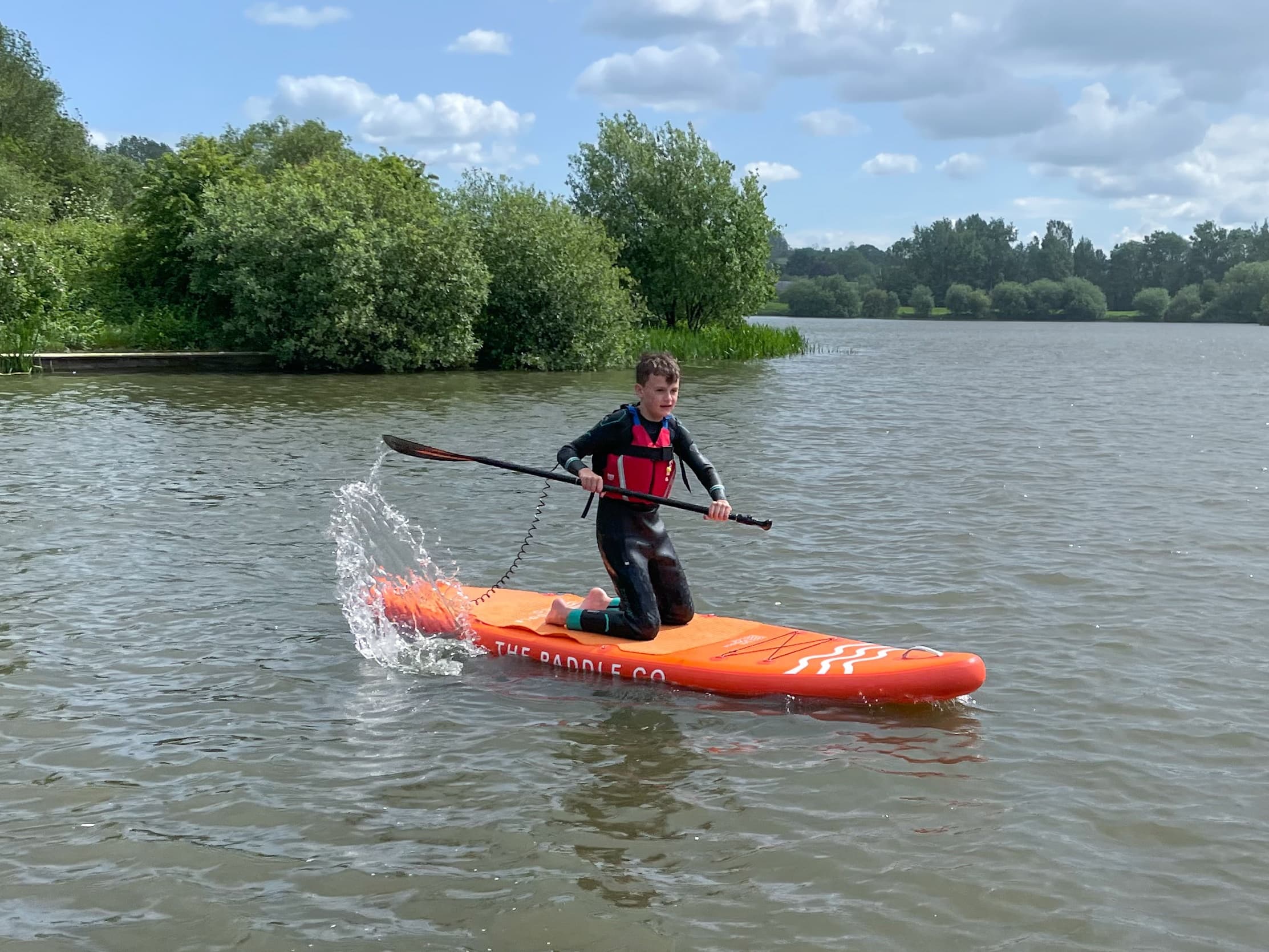 Person stand-up paddling on lake with energetic splash