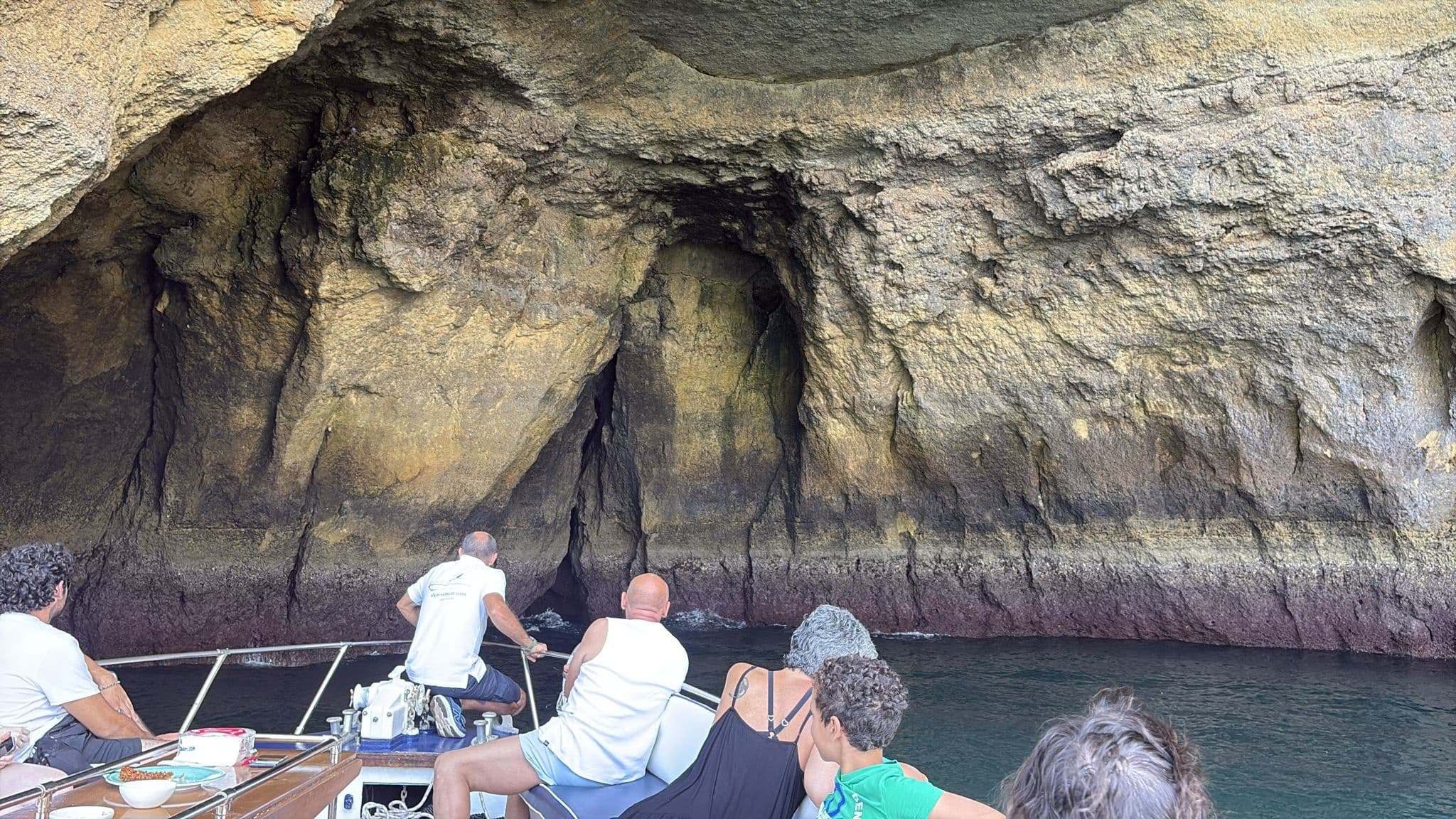 Tourists on boat entering Algarve sea cave and rock formations