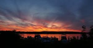 Coastal sunset skyline reflecting over calm harbor waters