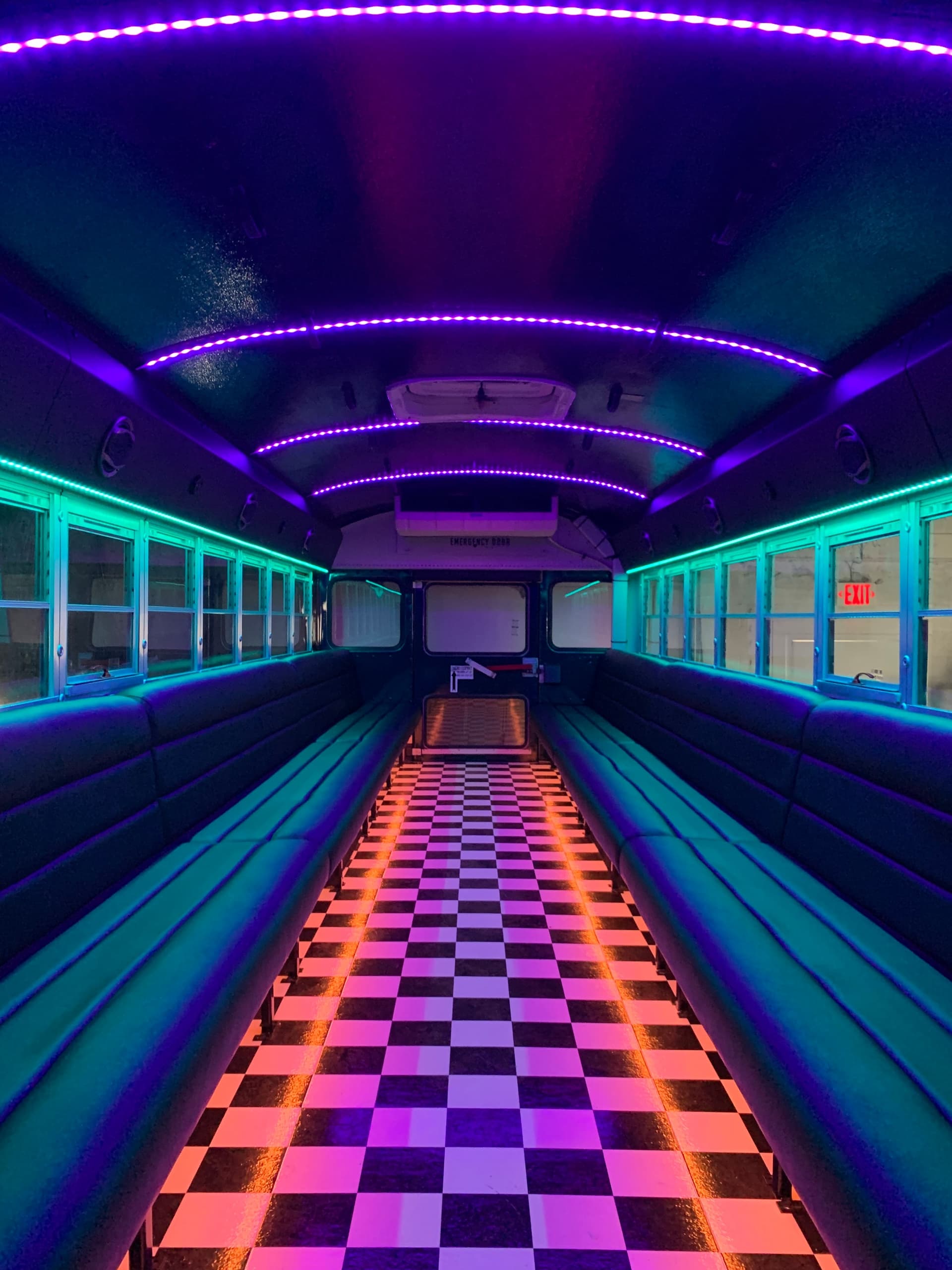 Neon-lit party bus interior with lounge seating and checkered aisle
