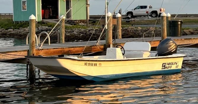 Small skiff fishing boat tied to dock in coastal inlet