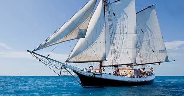 Traditional schooner sailing on open blue ocean under clear sky