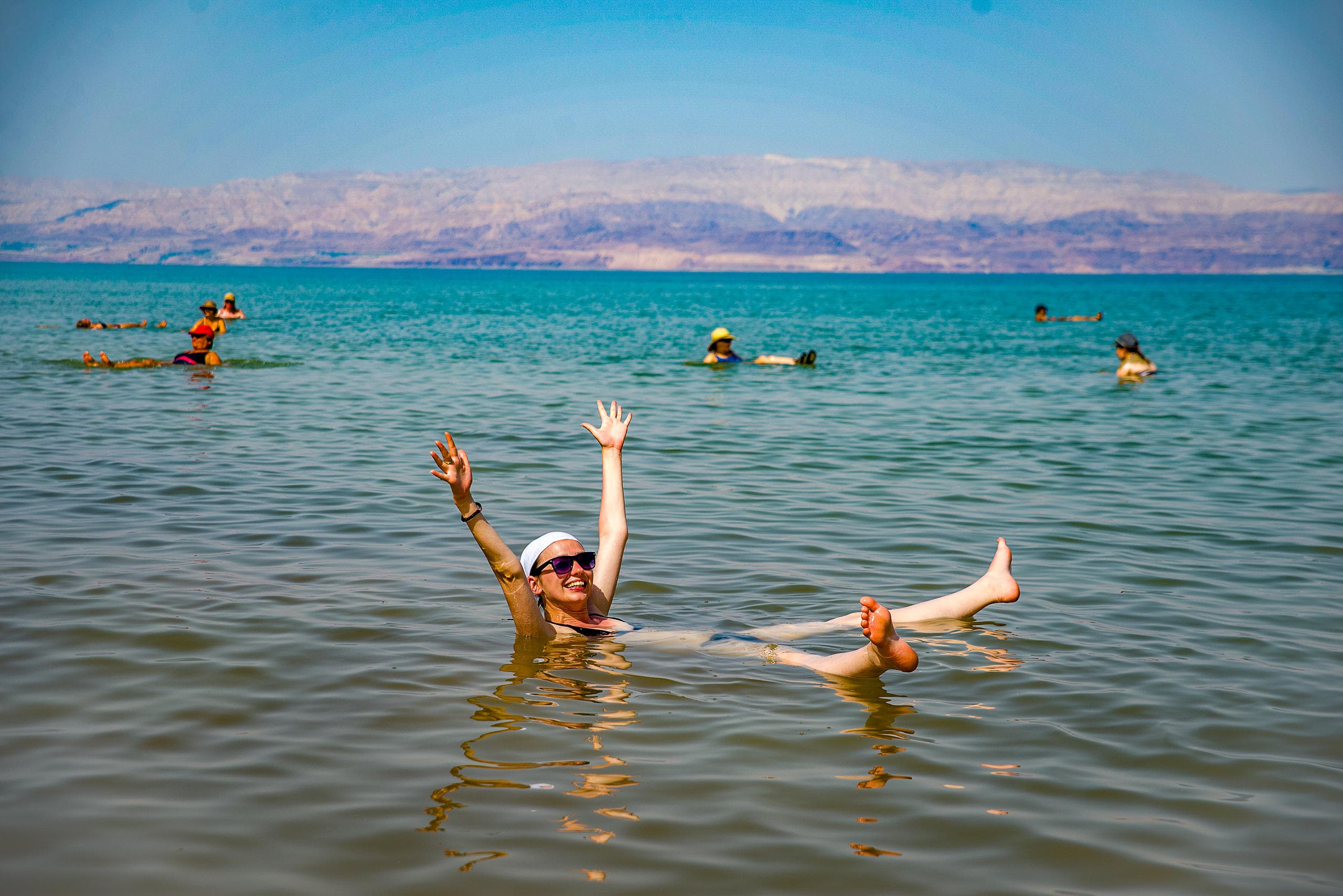 Tourists floating in Dead Sea enjoying buoyant salt water