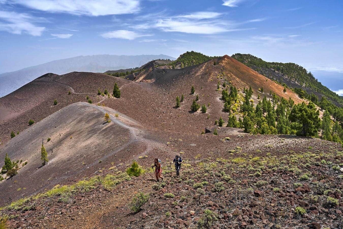 Hikers trekking volcanic crater trail with ocean views La Palma