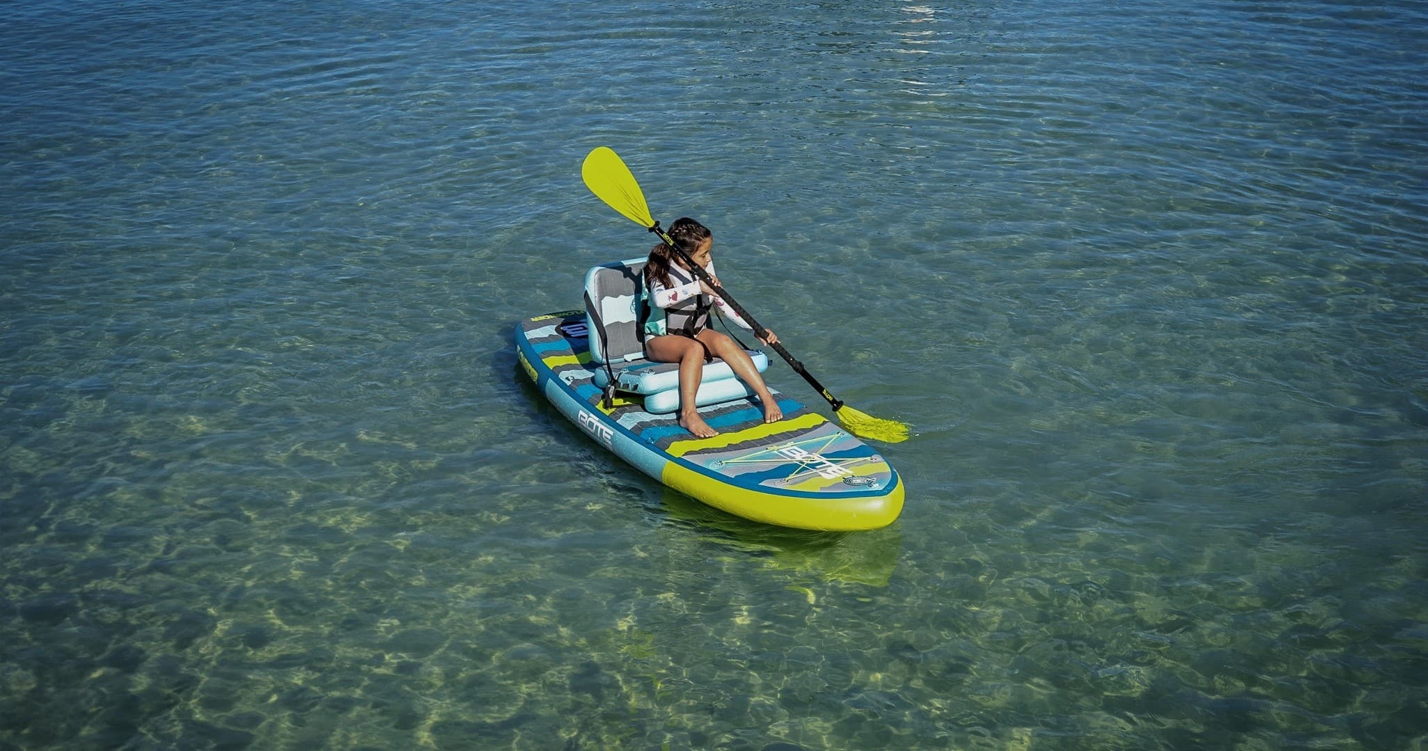 Solo kayaker paddling in clear green-tinted coastal waters near shore