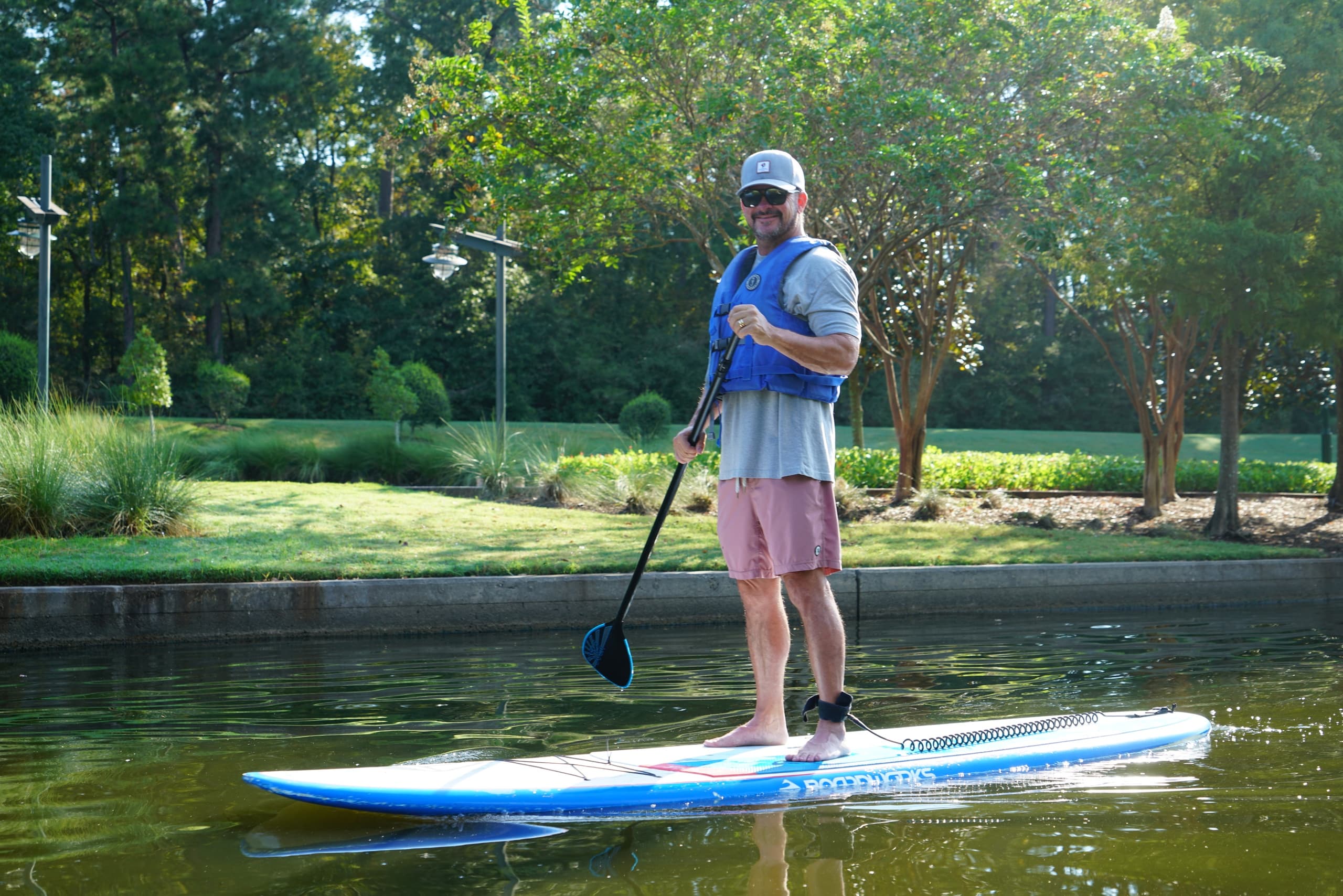 Solo paddleboarder standing and paddling on a scenic park lake