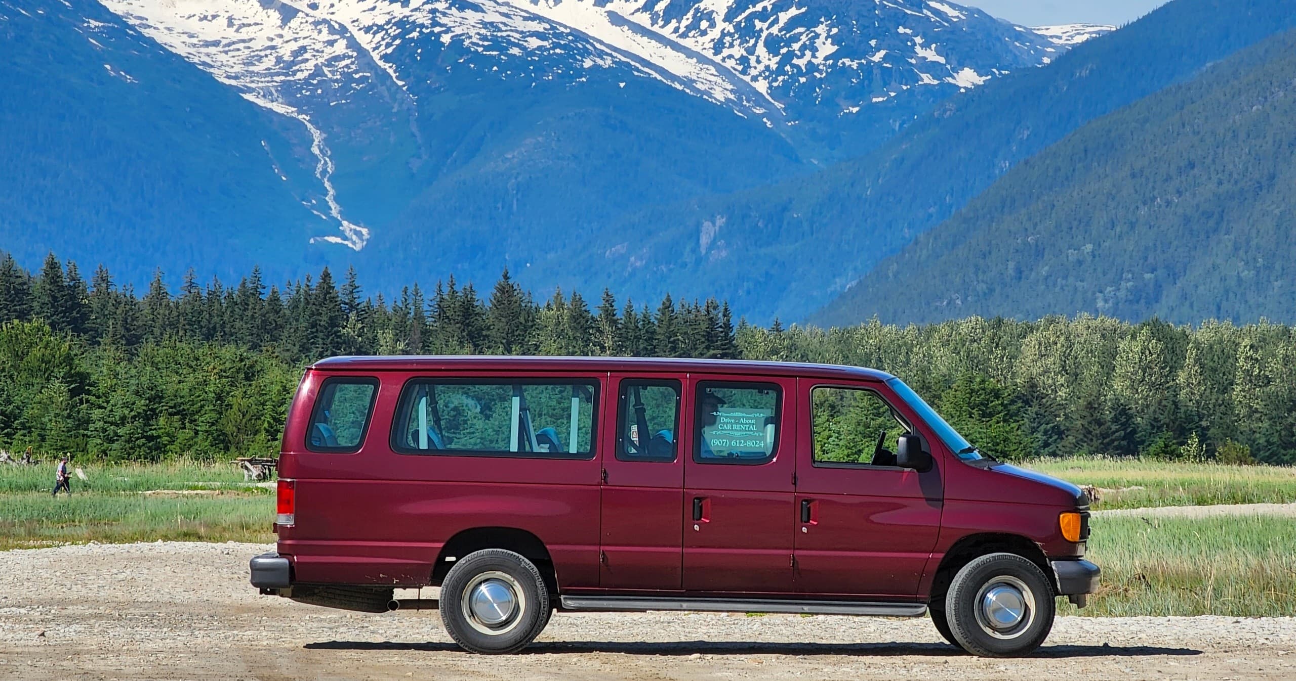 Red camper van parked beside alpine valley with mountain vista