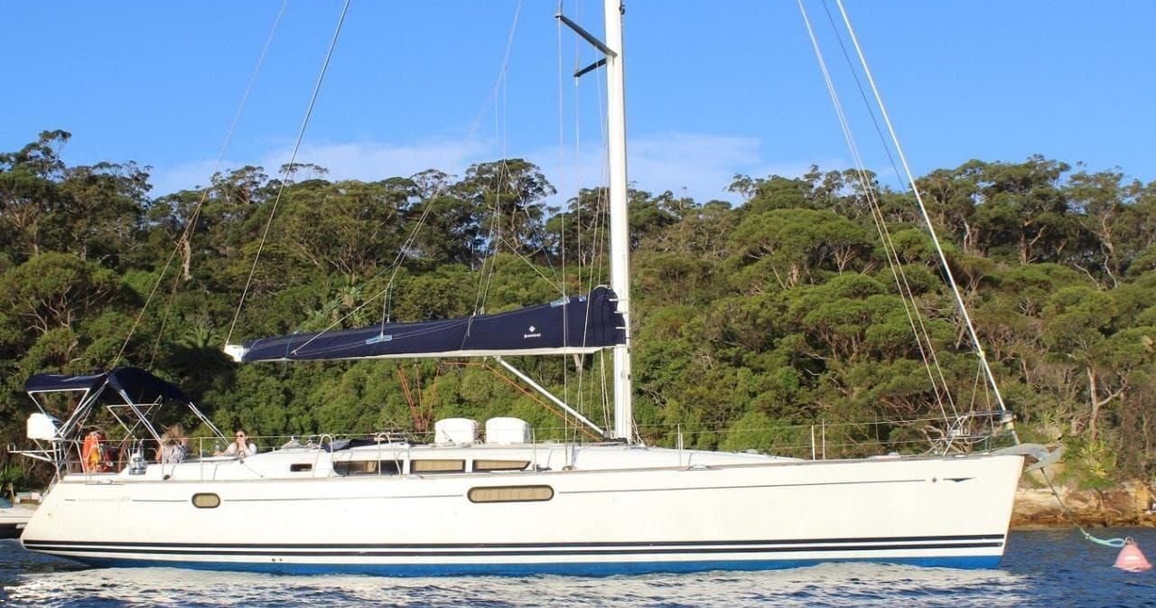 White sailing yacht moored near bushy headland for coastal charter