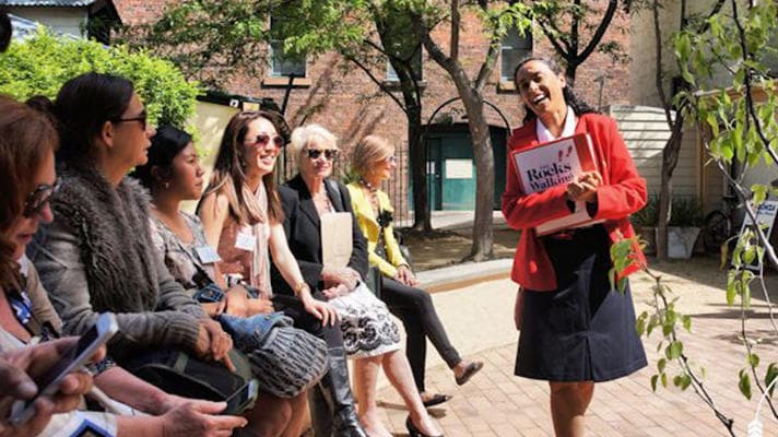 Guided walking tour in sunlit courtyard with guide speaking