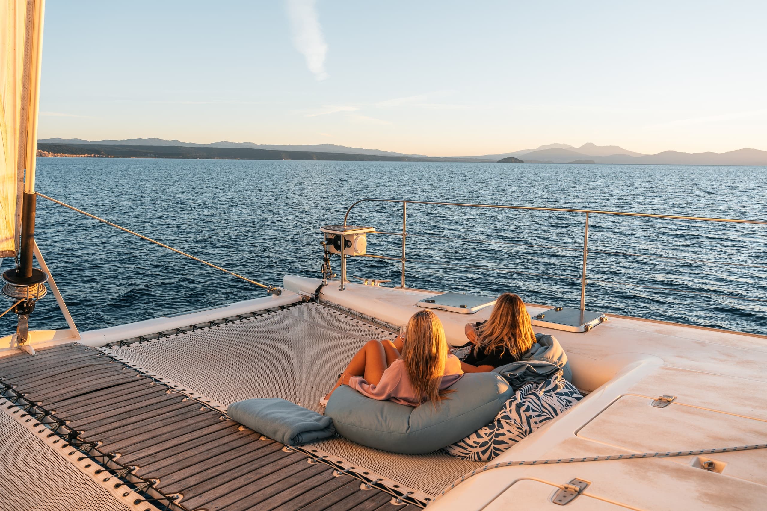 Couple relaxing on yacht foredeck watching sunset over sea