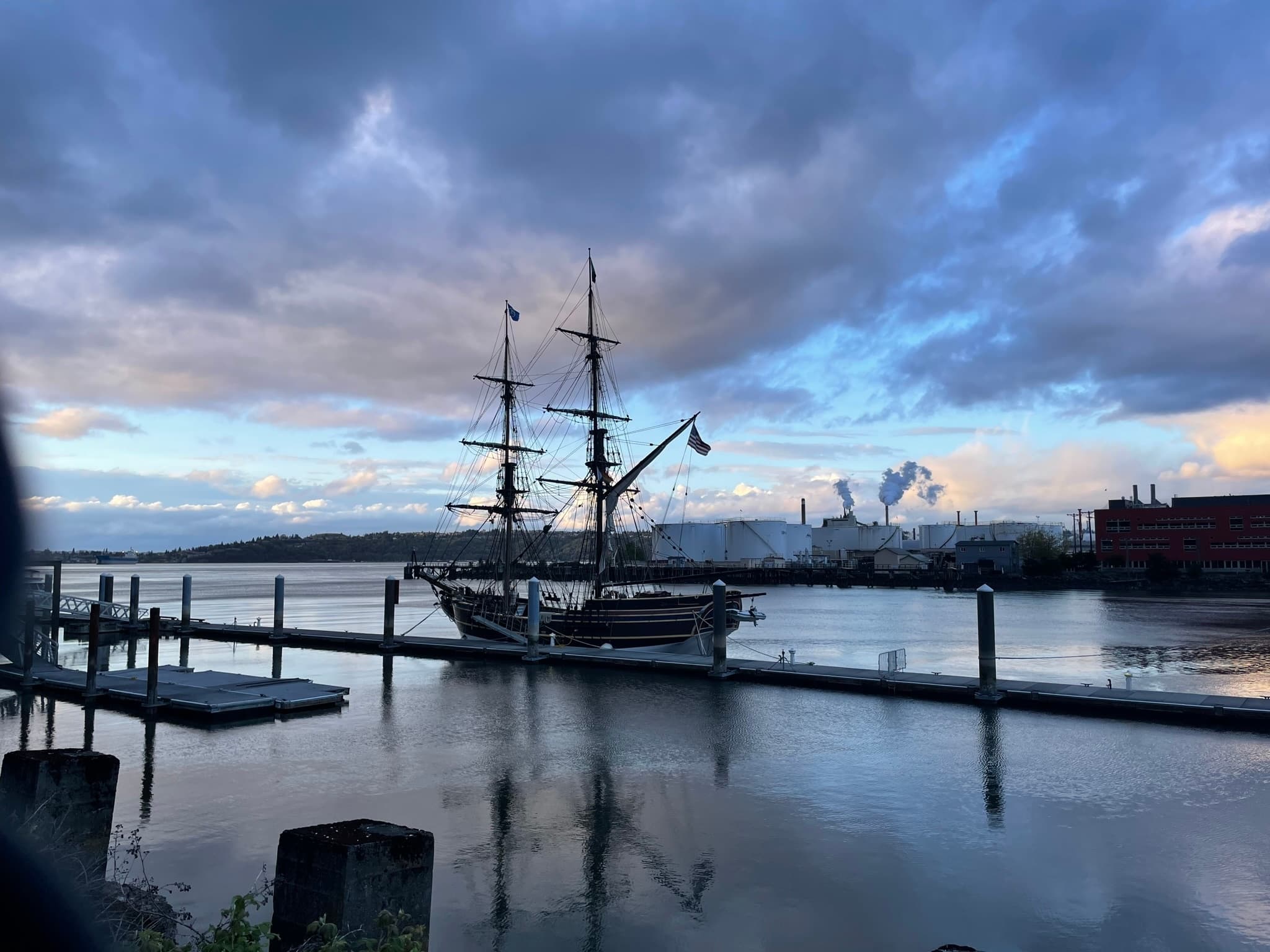 Historic tall ship moored at harbor at sunset with dramatic sky