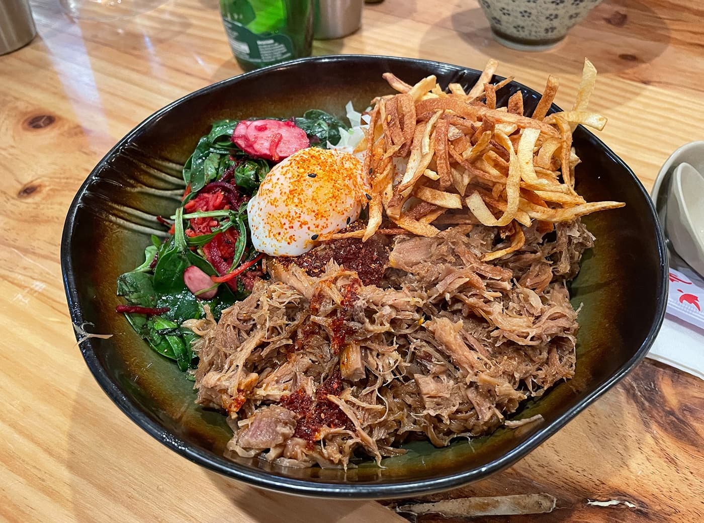 Pulled pork bowl with soft egg and shoestring fries in casual eatery
