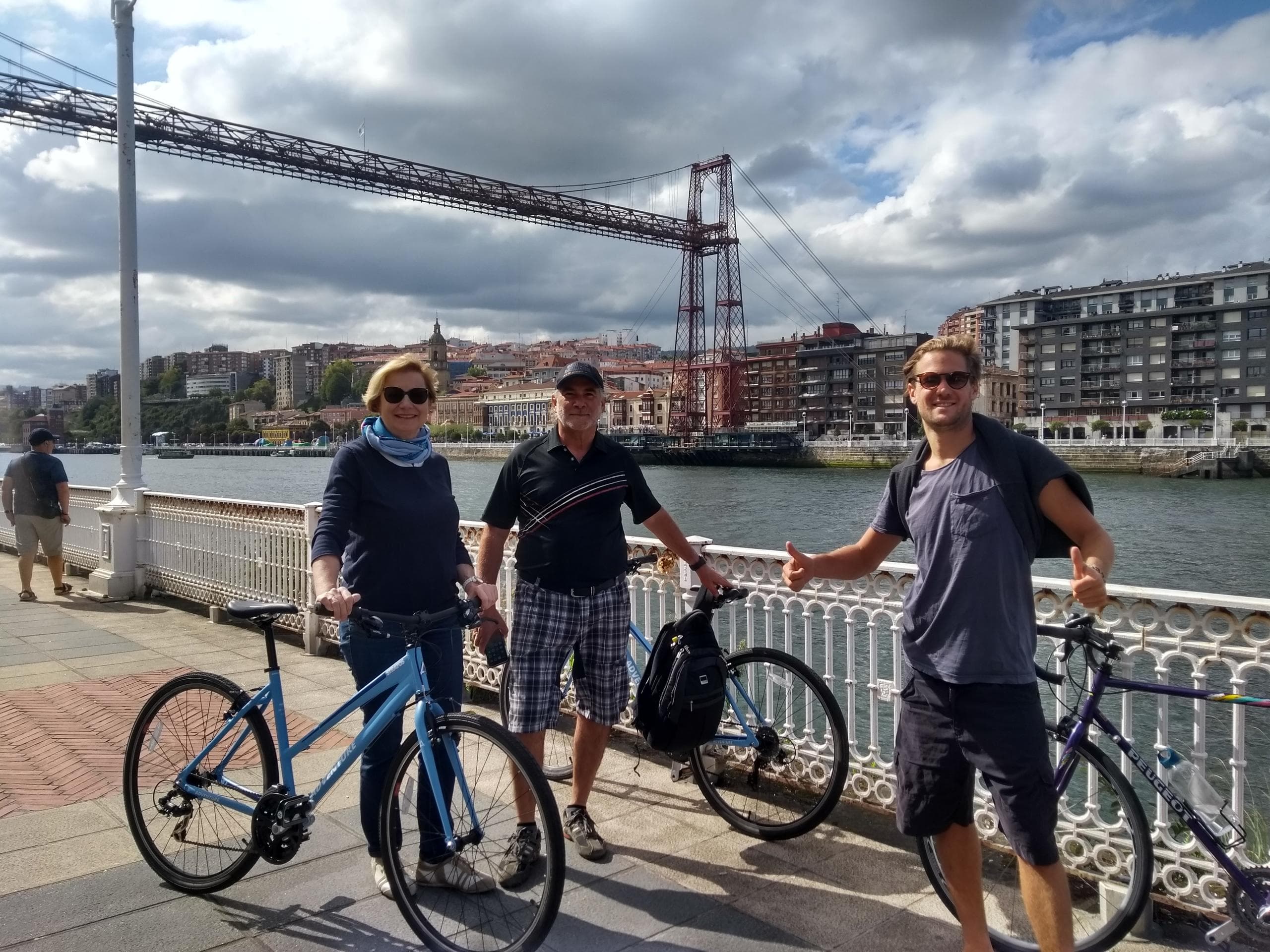 Friends with rental bikes by Vizcaya bridge on Bilbao riverside tour